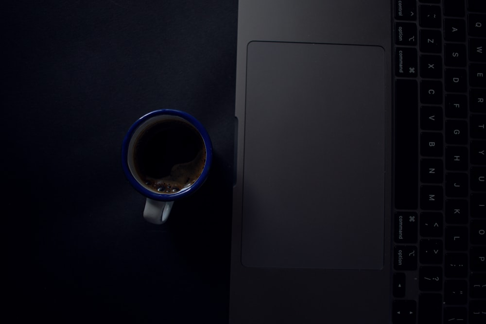 a cup of coffee sitting on top of a laptop computer