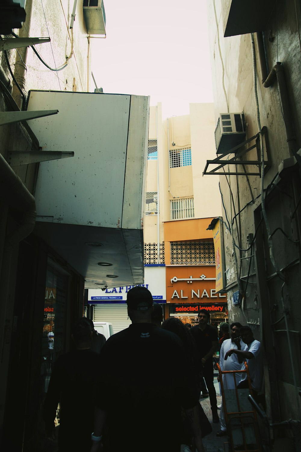 a group of people walking down a street next to tall buildings