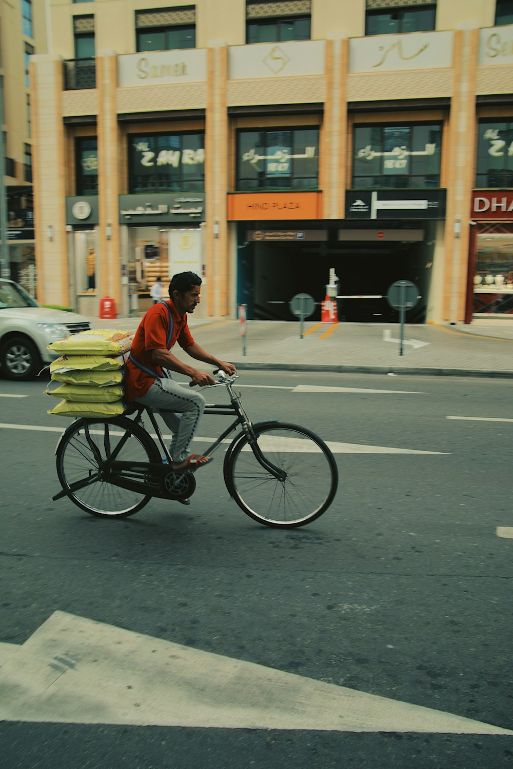 a man riding a bike down a street next to a tall building