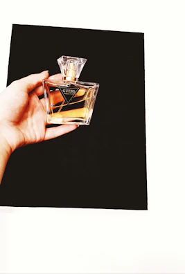 Close-up of a hand holding a Maison Sahar Perfumerie bottle against a backdrop of sand-colored fabric