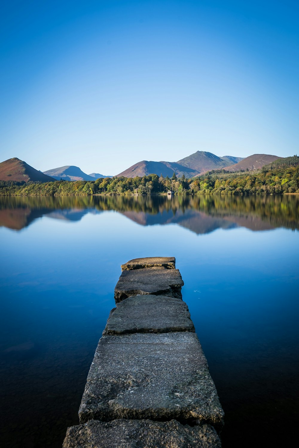 a long stone wall sitting next to a body of water