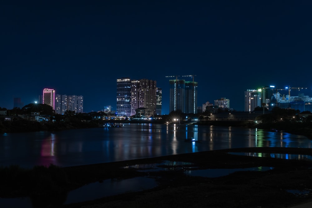 a night view of a city with a lake in the foreground