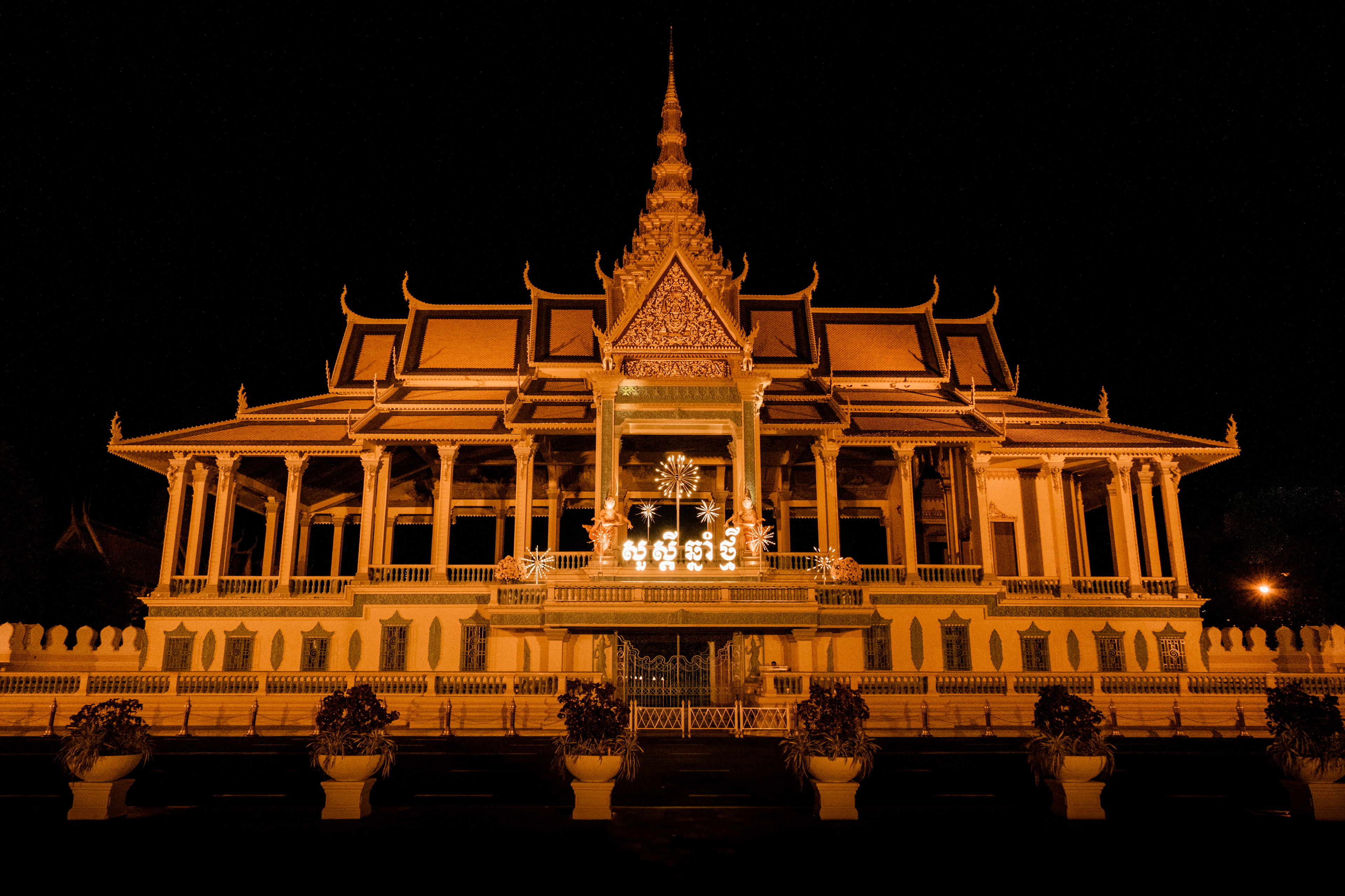 A pavilion of the Royal Palace in Phnom Penh lit gold against the night, its tiered roof and finials picked out