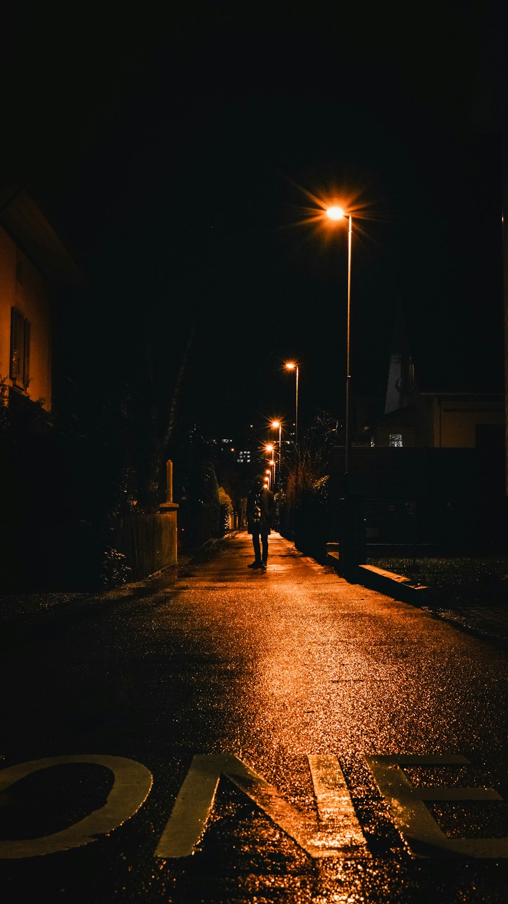 a street at night with a person walking down the street