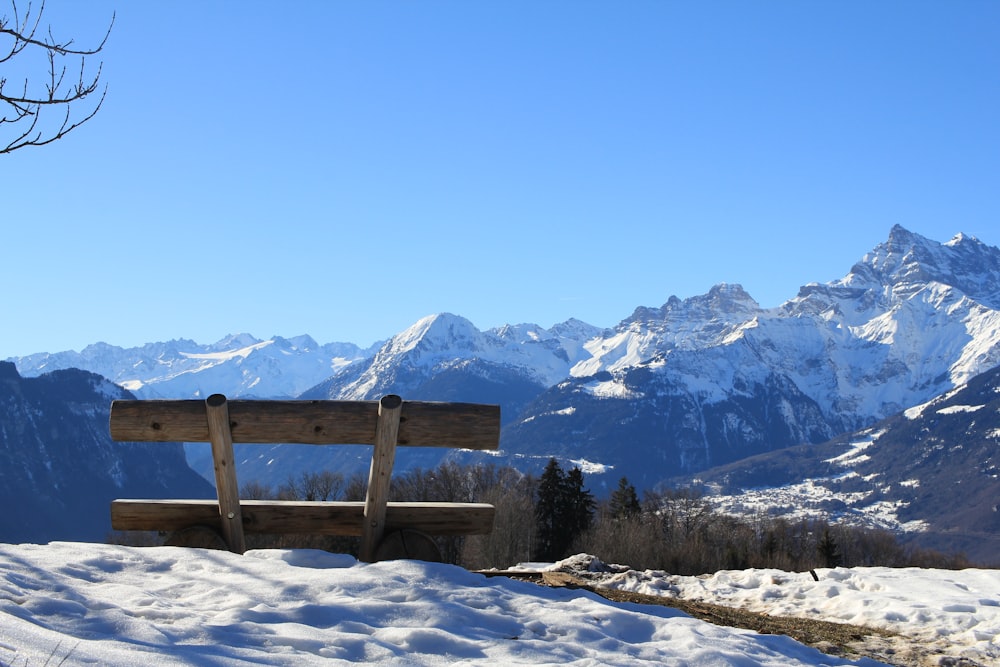 a wooden bench sitting on top of a snow covered slope