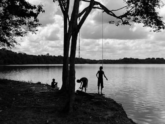 Children playing by a serene lake with trees and wildlife in the background.