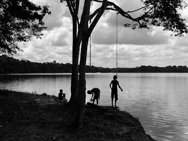 Children playing by a serene lake with trees and wildlife in the background.