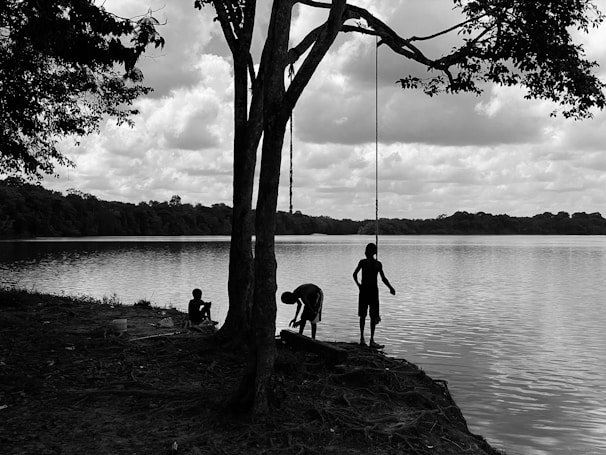 Children playing joyfully under the gentle shade of the beloved tree of life silhouette.