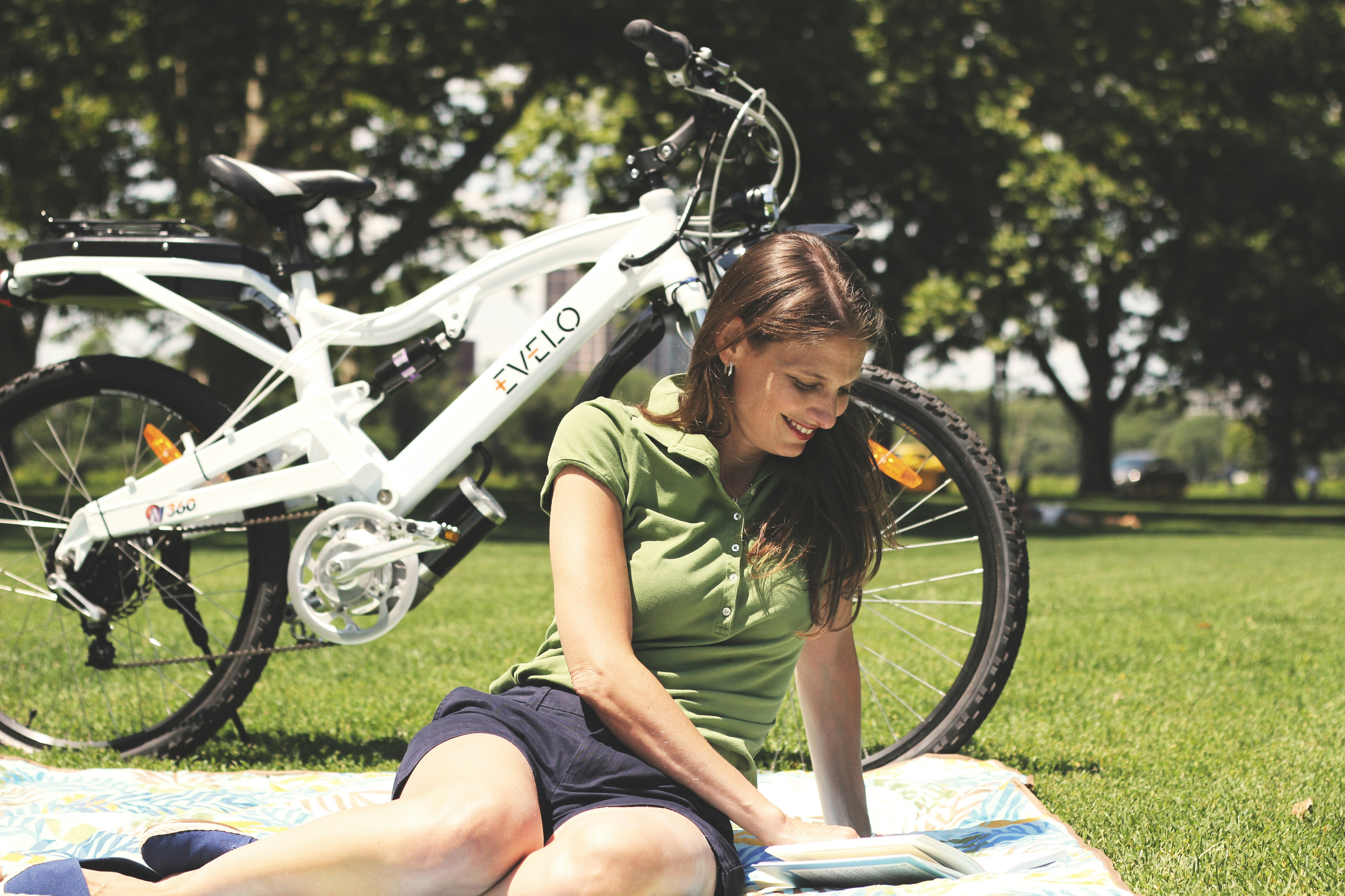 a woman sitting on a blanket next to a bicycle