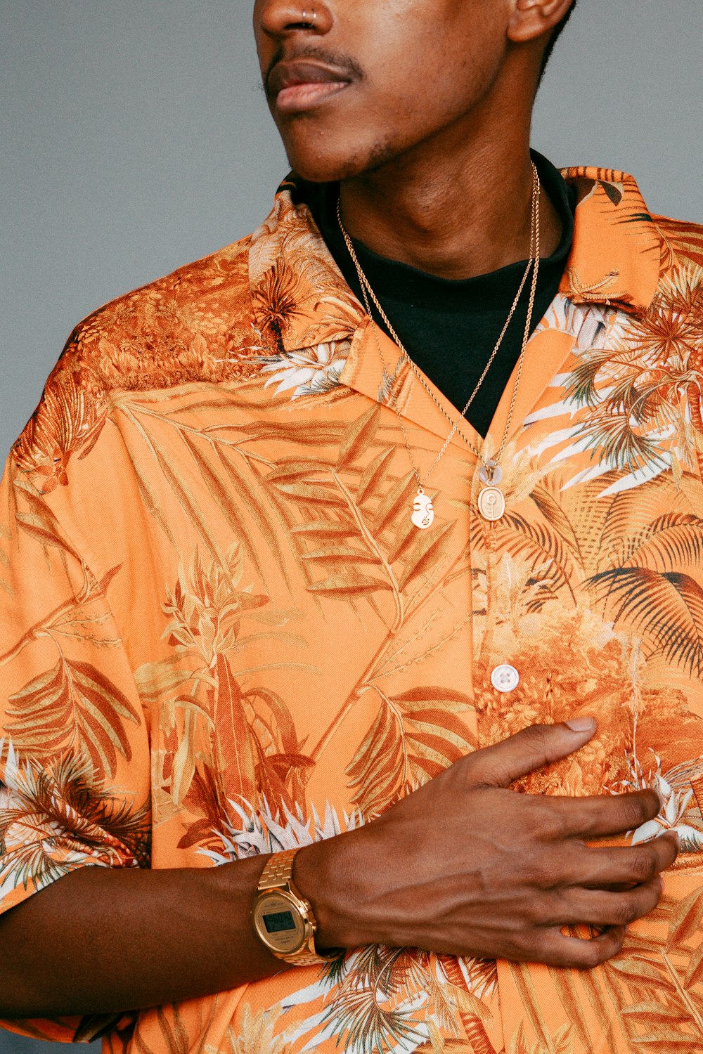 a man wearing an orange hawaiian shirt with palm leaves on it