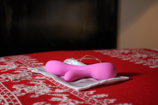 A soft blush pink coin pouch resting on a creamy off-white fabric with gentle sunlight.