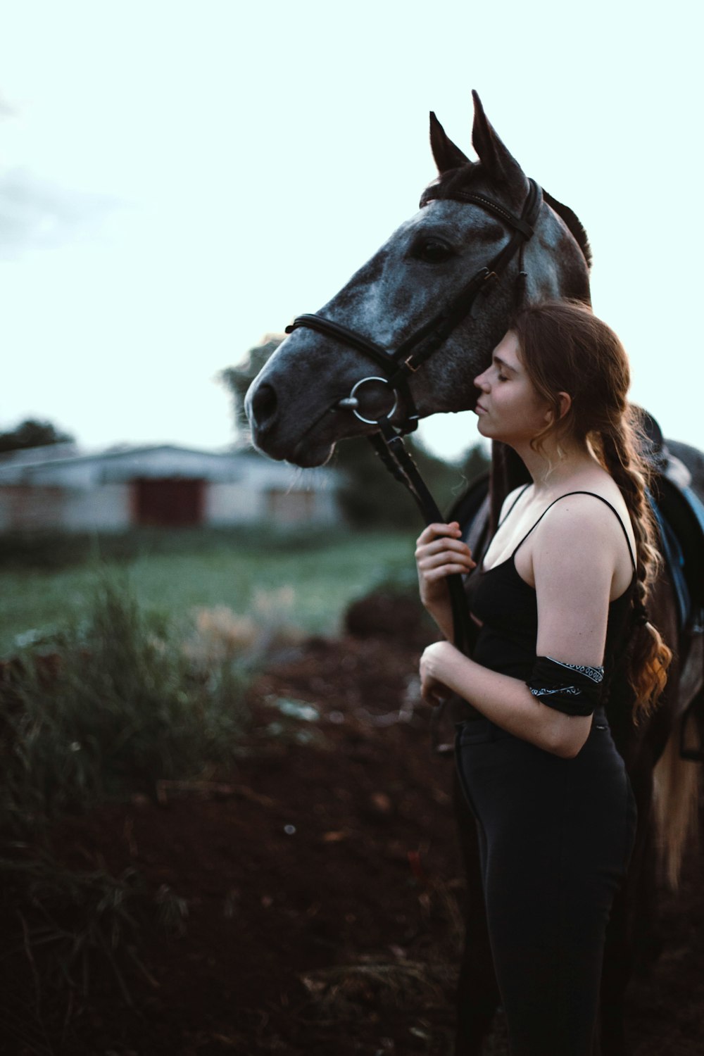 a woman standing next to a horse in a field