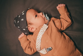 a baby wearing a hat and tie laying on a bed