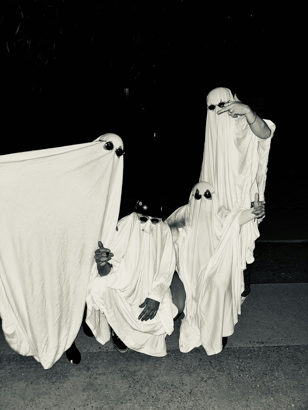 a black and white photo of three people dressed in ghost costumes