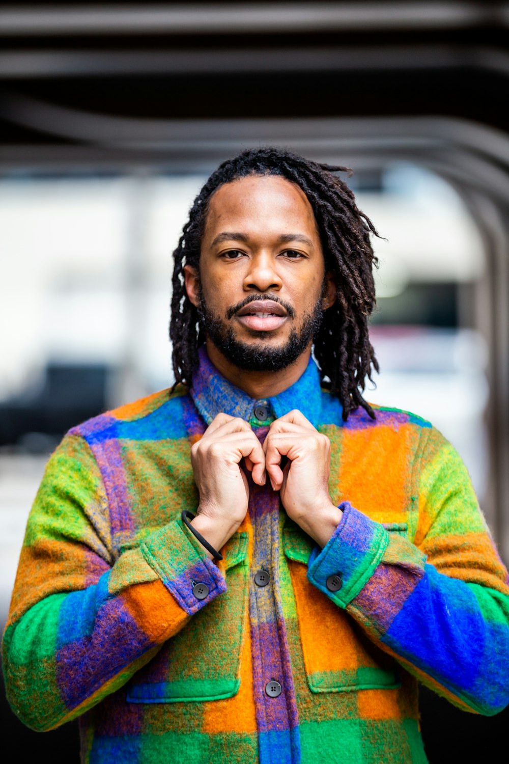 a man with dreadlocks standing in front of a building