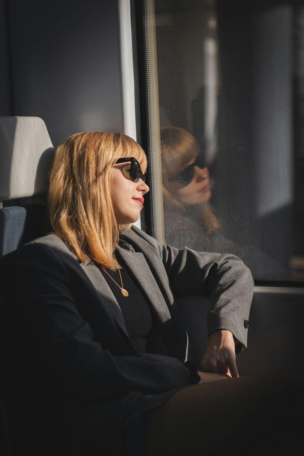 a woman wearing sunglasses sitting on a train