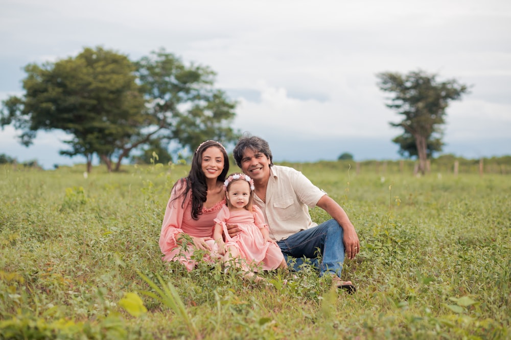 a man, woman and child are sitting in a field