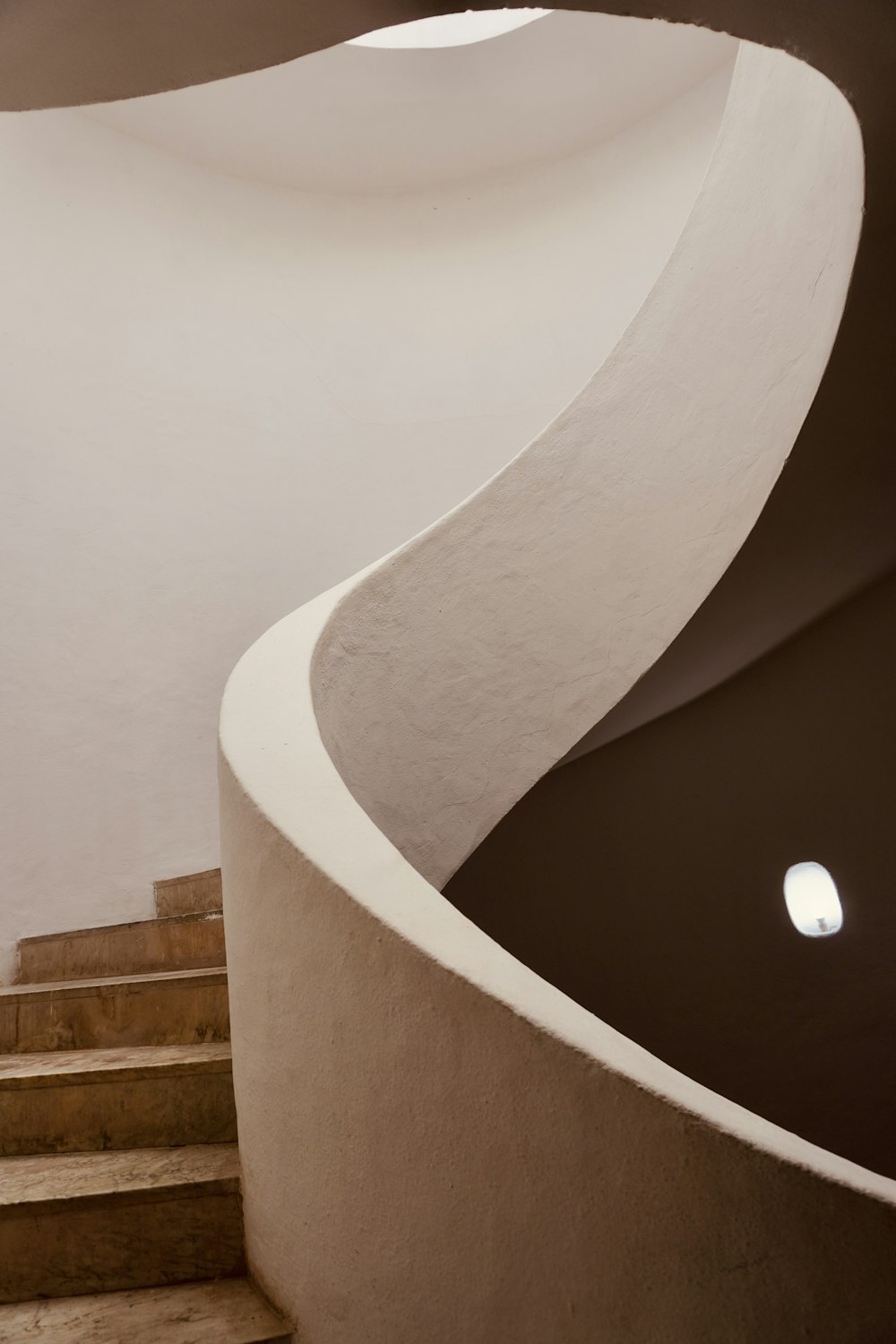a curved staircase with a circular light at the top
