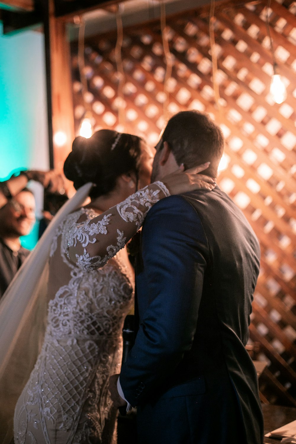 a bride and groom kissing in front of a screen