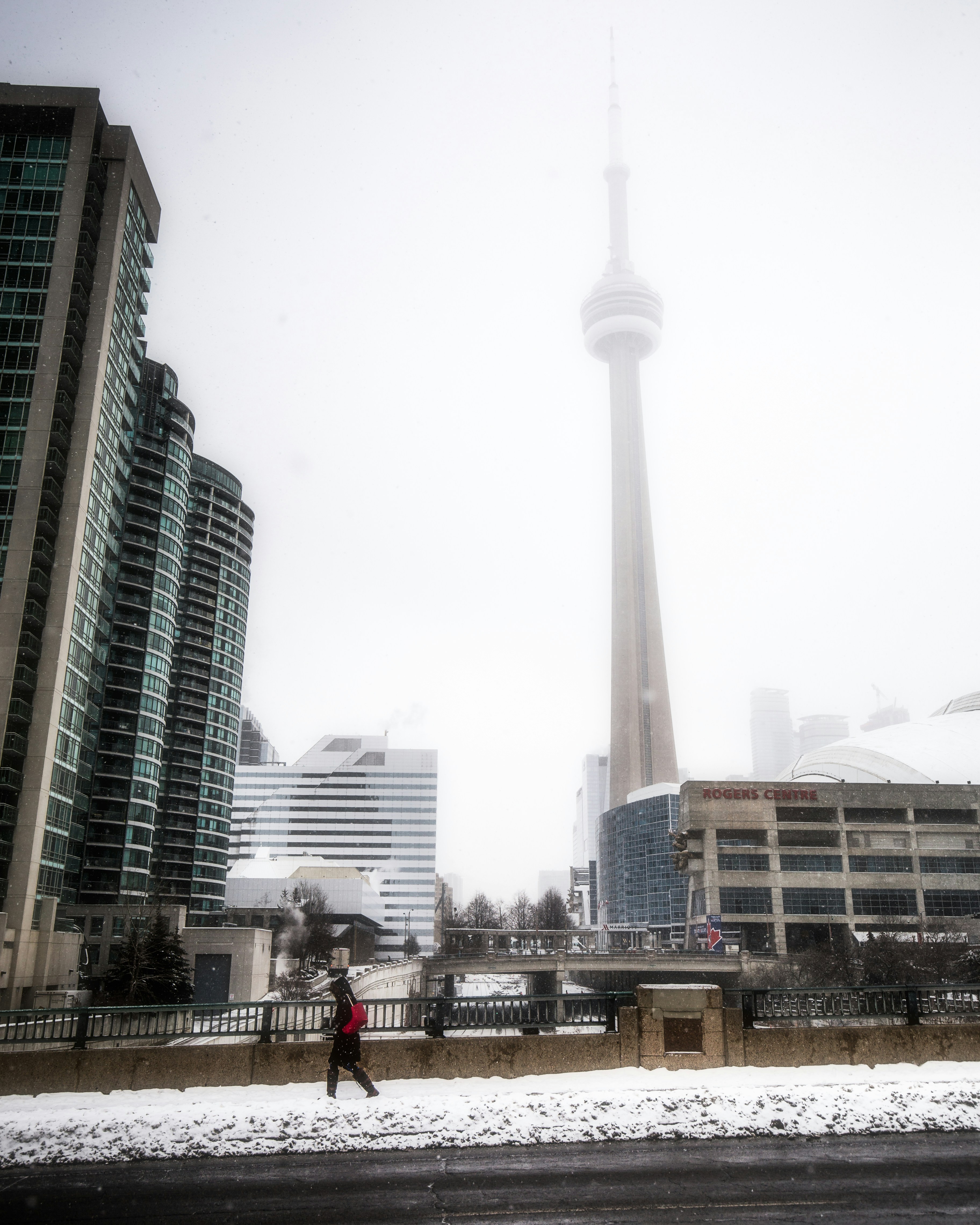 a person walking in the snow in front of a tall building