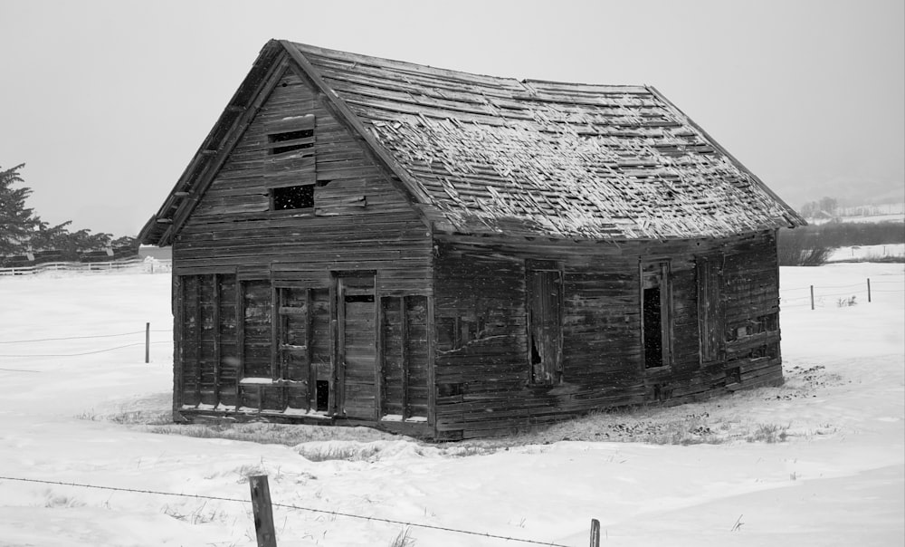 a black and white photo of an old house in the snow