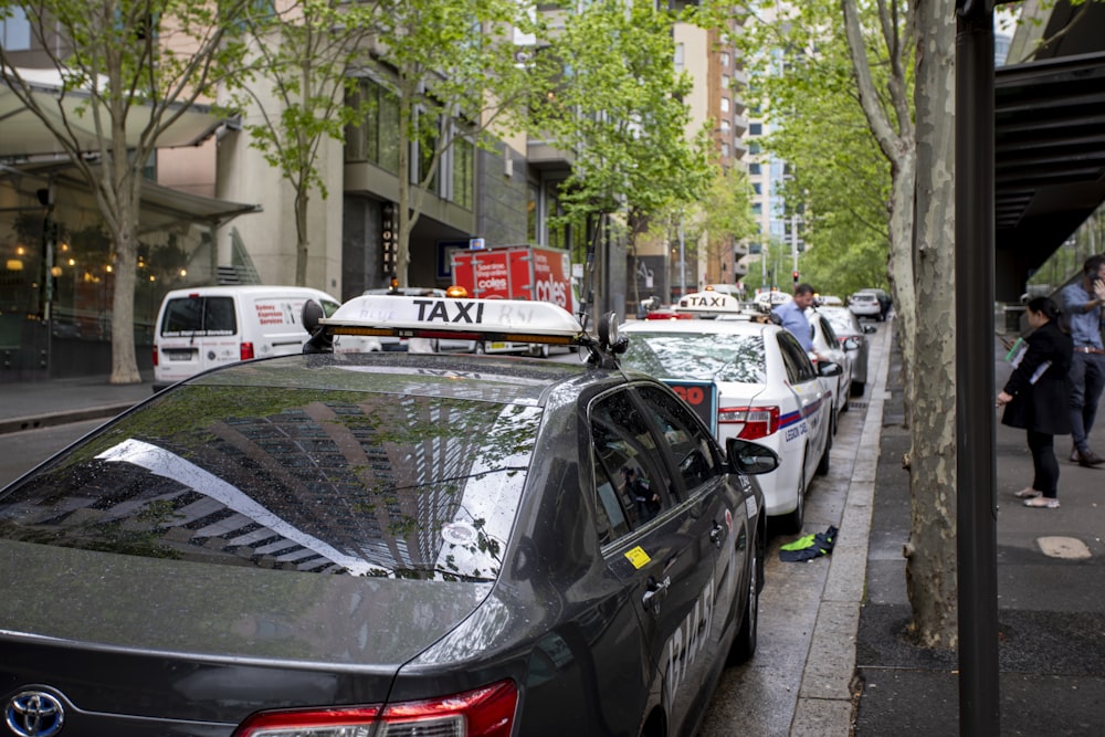 a line of taxi cabs parked on the side of a street
