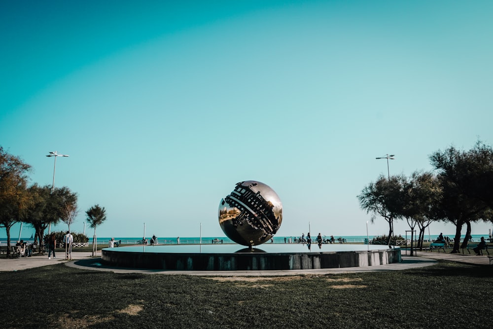 a sculpture in the middle of a park near the ocean