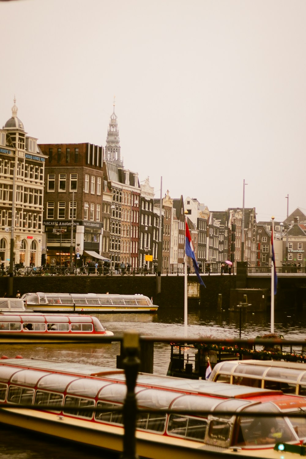 a river filled with lots of boats next to tall buildings