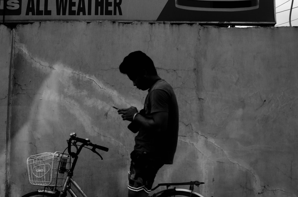 a man standing next to a bike while using a cell phone