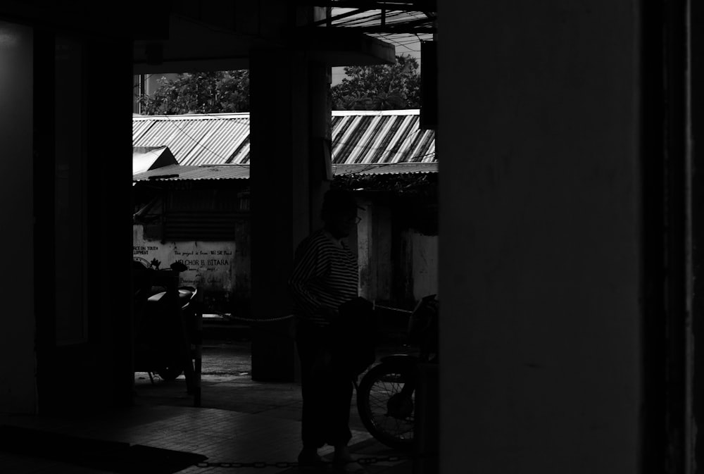 a black and white photo of a man standing in a doorway