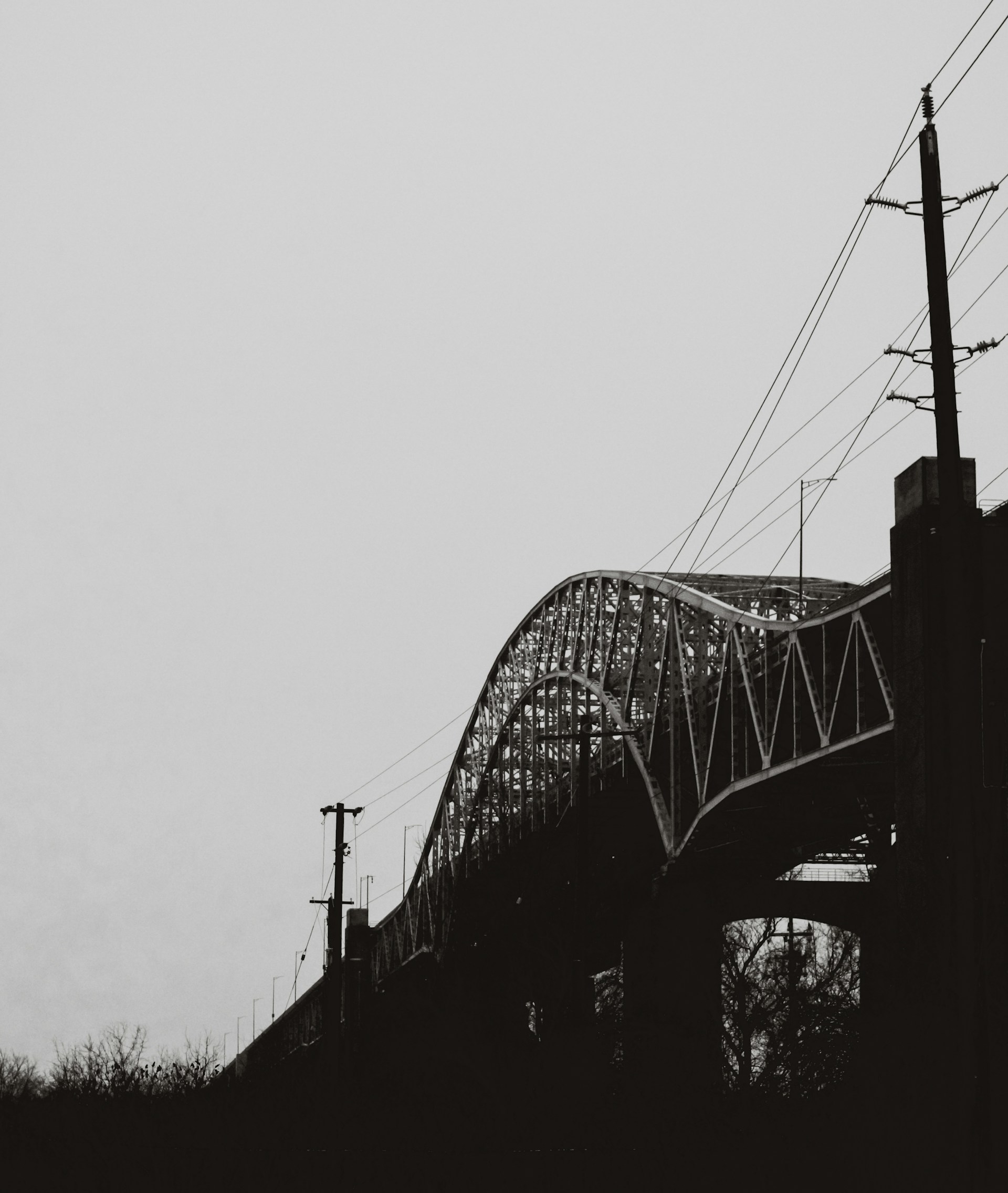 a black and white photo of a bridge and power lines
