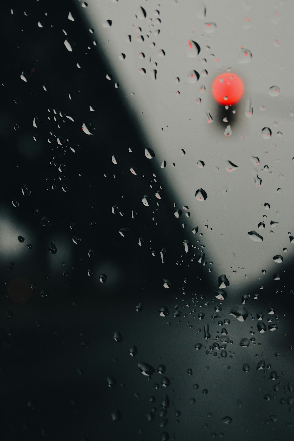 rain drops on a window with a red light in the background