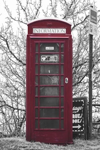 a red telephone booth sitting next to a street sign