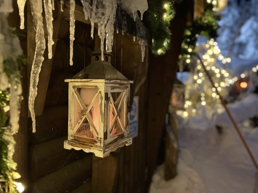 a lantern hanging from a wooden fence covered in snow