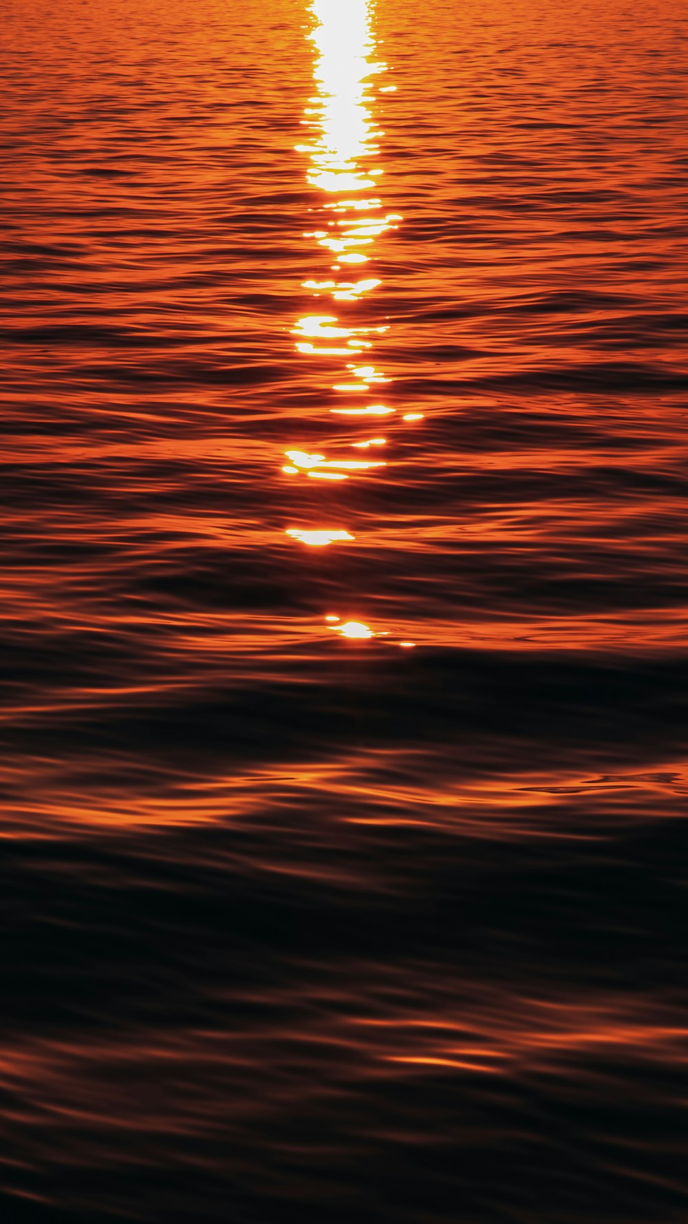 a large body of water with a sunset in the background