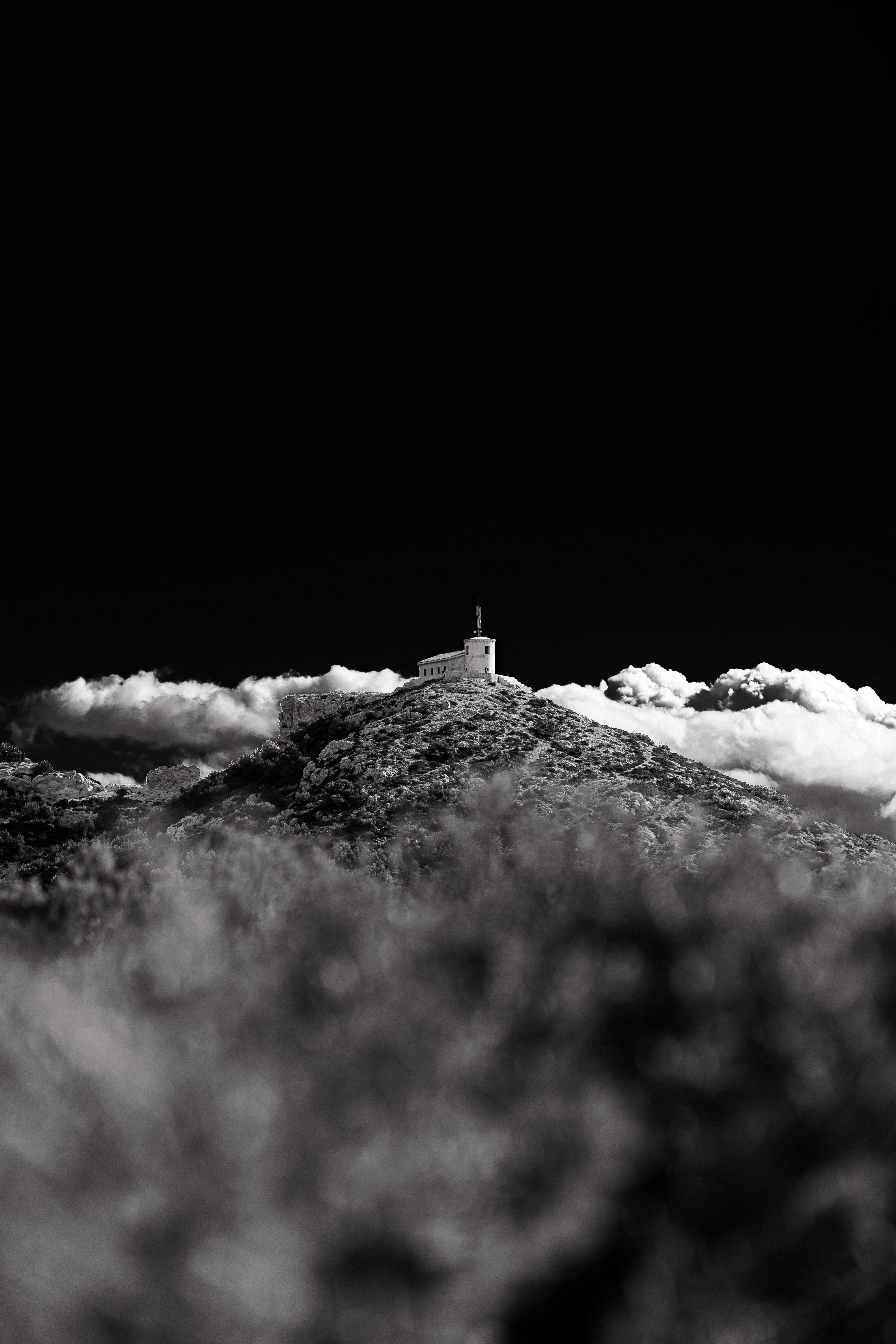 a black and white photo of a lighthouse on a hill