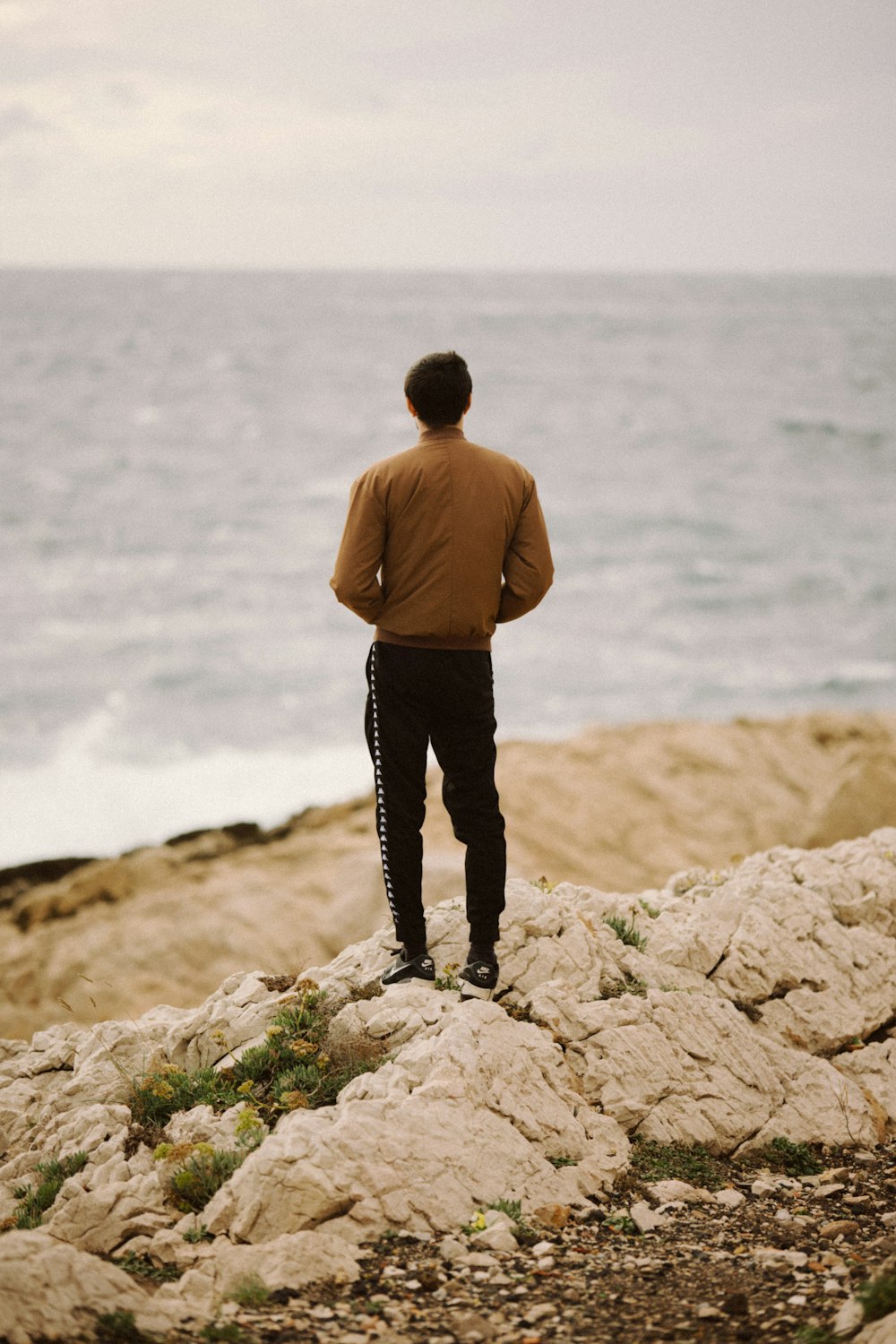 a man standing on top of a rocky beach next to the ocean