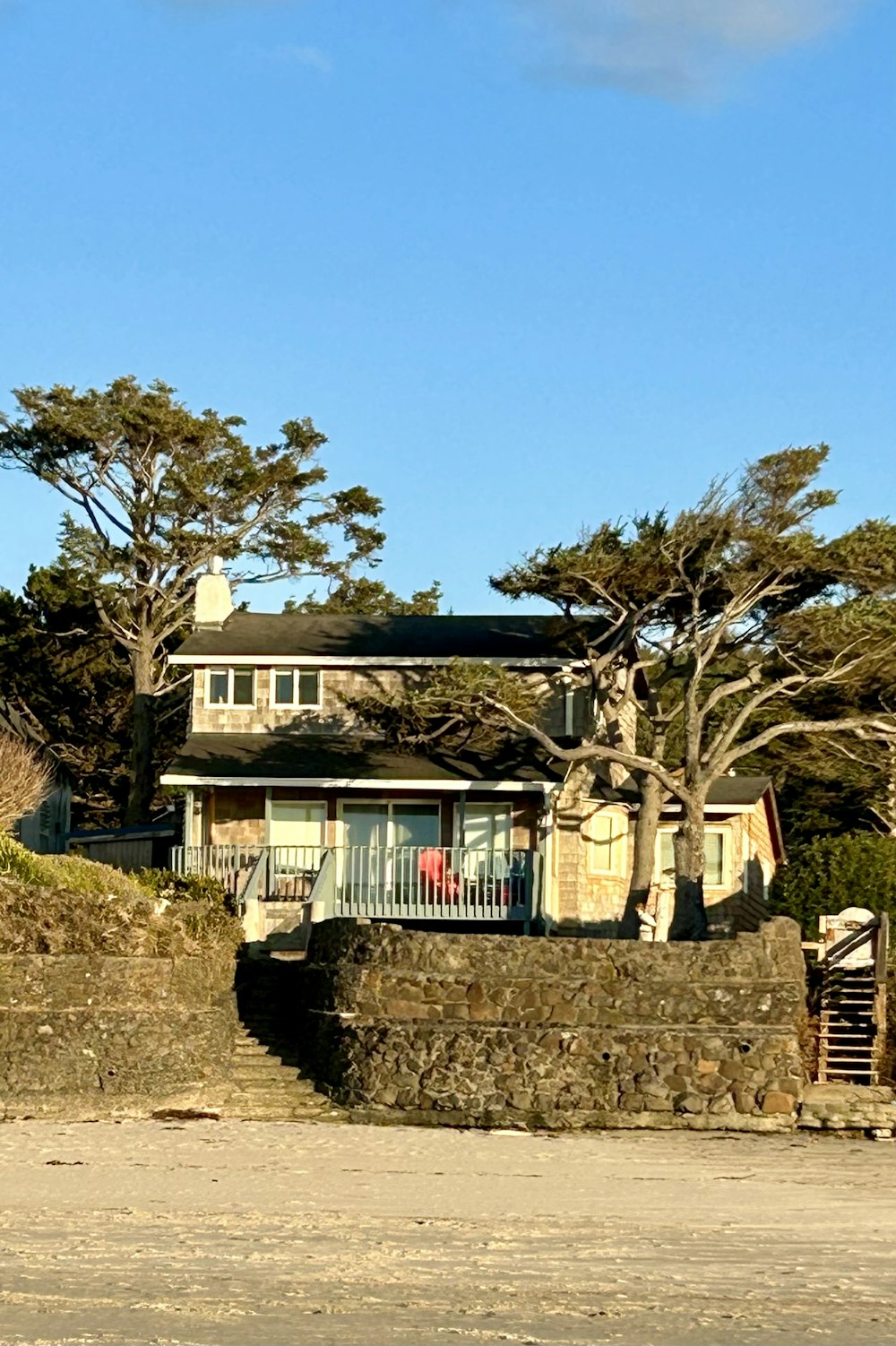 a house on the beach with a surfboard in front of it