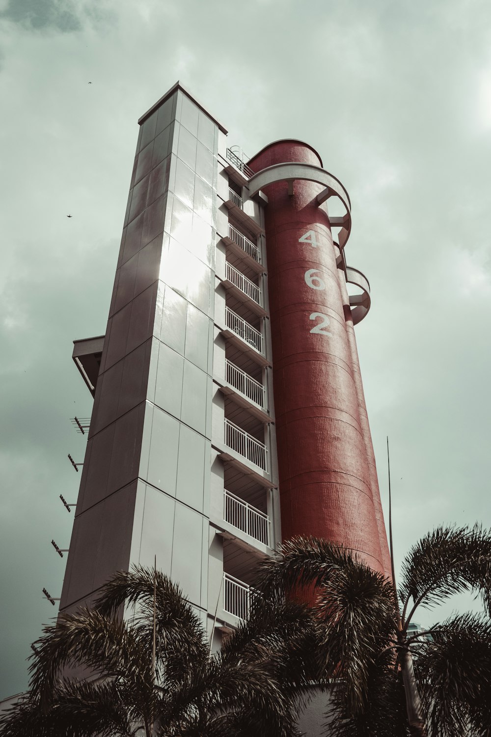 um edifício alto vermelho e branco ao lado de palmeiras