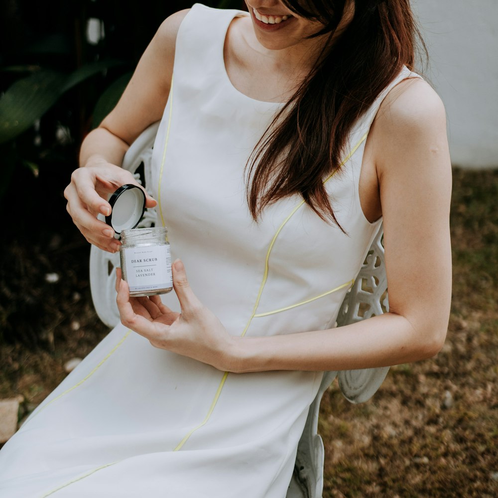 a woman in a white dress holding a jar