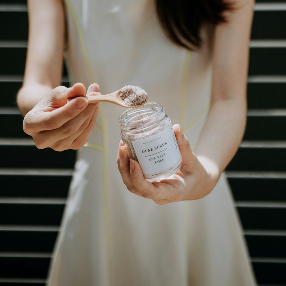 a woman holding a jar of sugar and a spoon