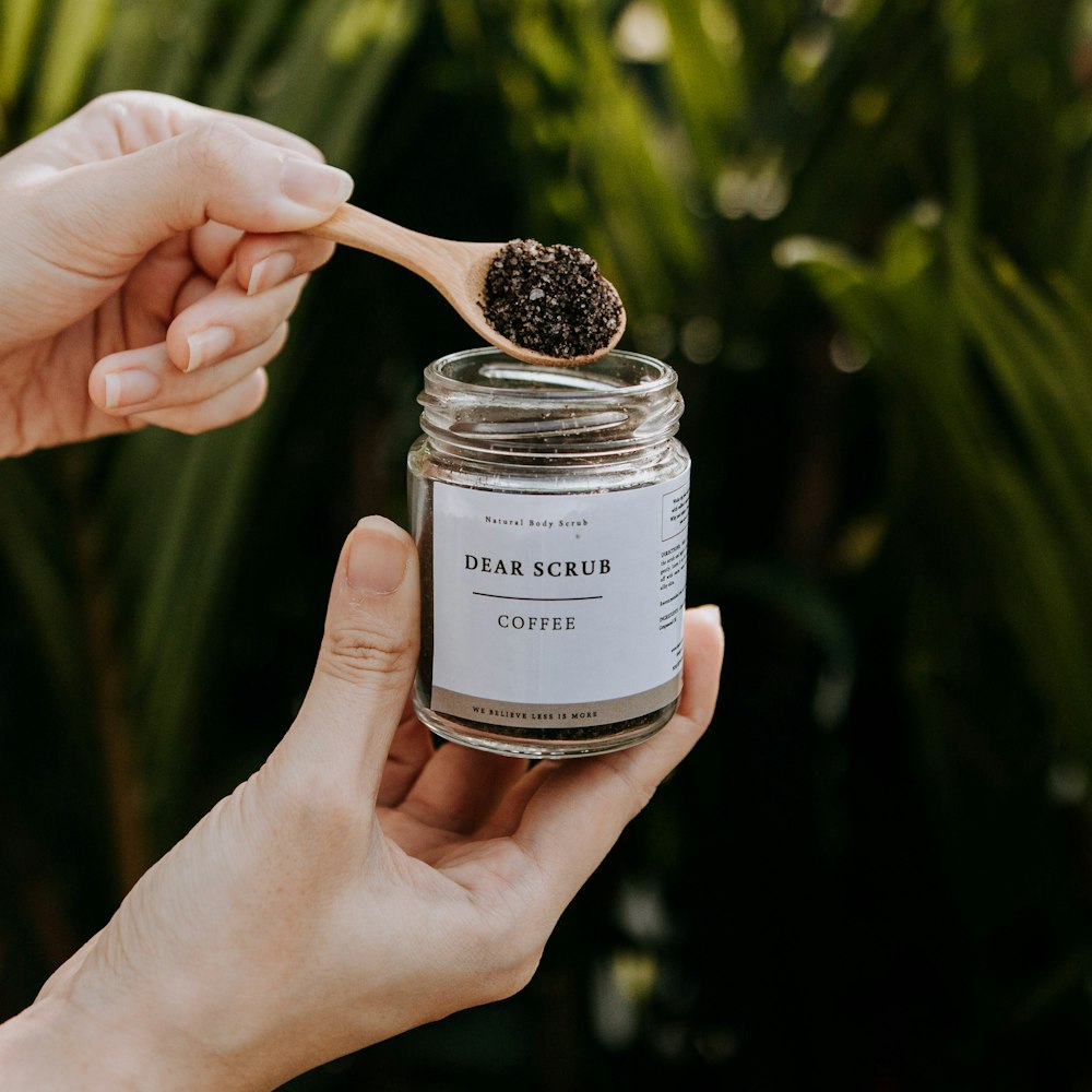 a person holding a jar of coffee with a spoon in it