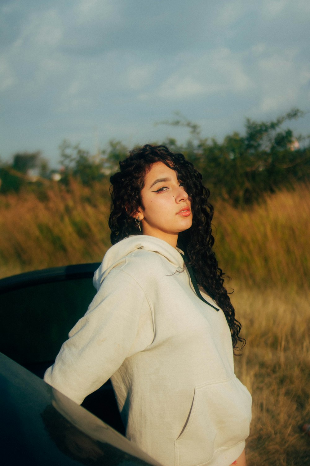 a woman standing next to a car in a field