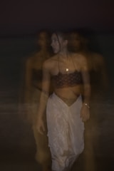 Fading image of a voodoo-inspired outfit blending shadows and vibrant colors.