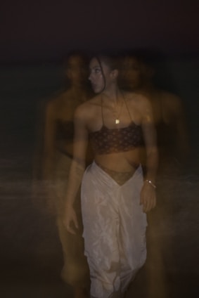 Fading image of a voodoo-inspired outfit blending shadows and vibrant colors.