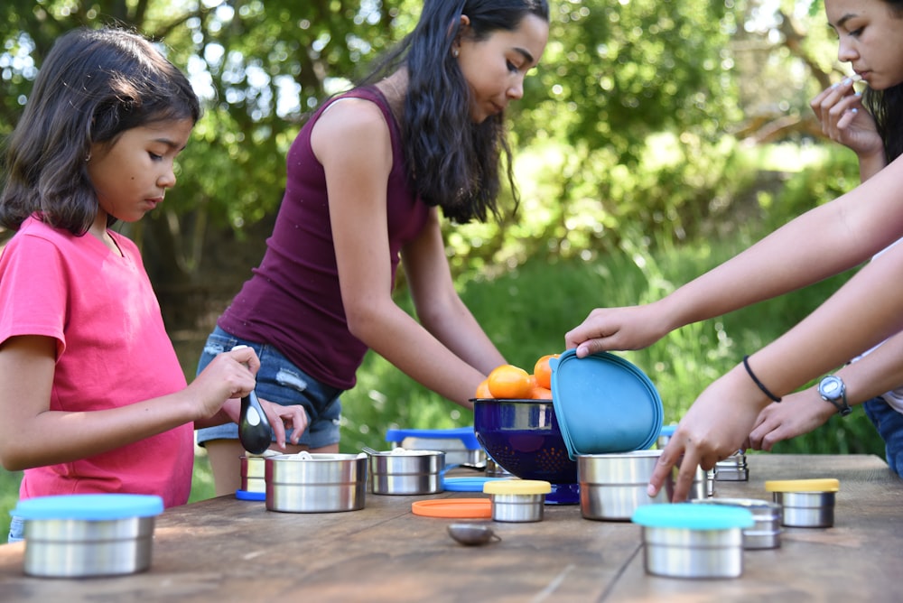 a group of people standing around a table with pots and pans