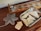 A wooden table holds a decorative object shaped like a snowflake next to a wooden board game with metal sliders. A metallic tray contains several smooth, cream-colored geometric shapes.