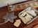 A wooden table holds a decorative object shaped like a snowflake next to a wooden board game with metal sliders. A metallic tray contains several smooth, cream-colored geometric shapes.