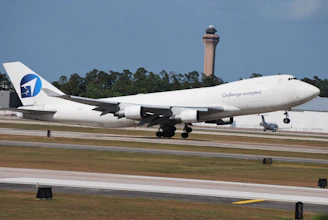A cargo plane taking off with international flags waving in the background.