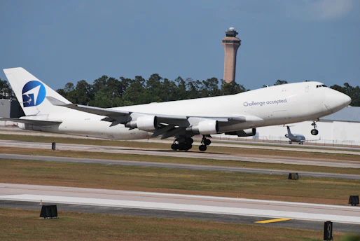 A cargo plane taking off with international flags waving in the background.